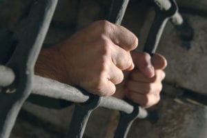 Man holding jail cell with hands