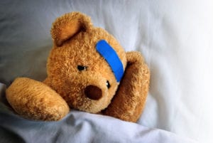 Hurt teddy bear in bed with band aid on his head