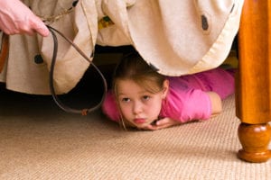 Girl hiding from parent under a bed