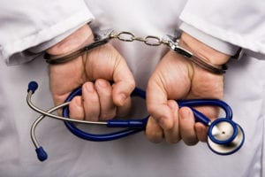 A doctor with handcuffs on holding a stethoscope