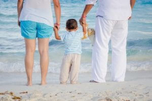 Parents on the beach holding young son's hands