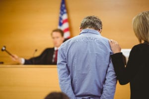 a man standing in court next to his attorney