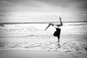 Woman doing handstand in water on the beach