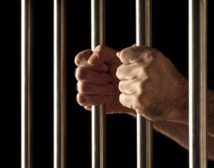 Man in jail holding bars