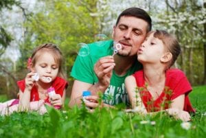 Father blowing bubbles with daughters