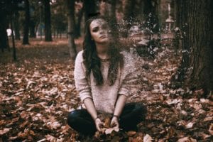 Woman sitting in woods and disintegrating