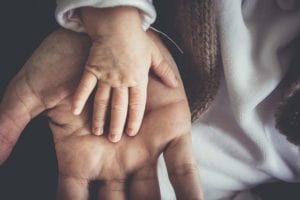 Child's hand overtop of parent's hand