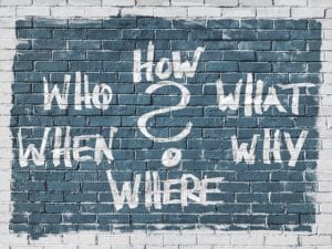 Who, how, what, why, where, when written on brick wall