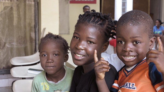 Three Haitian children sitting together - one boy and two girls.