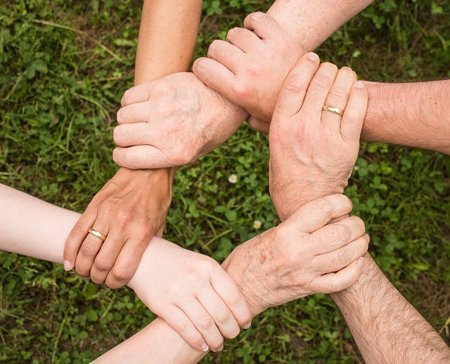 A circle of hands, each one holding on to the wrist of the next person, shows a circle of cooperation.