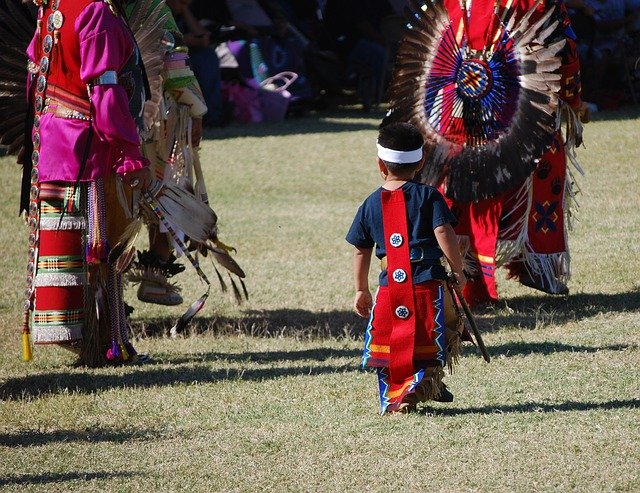 A group of Native Americans, including a child, in traditional dress on a field.