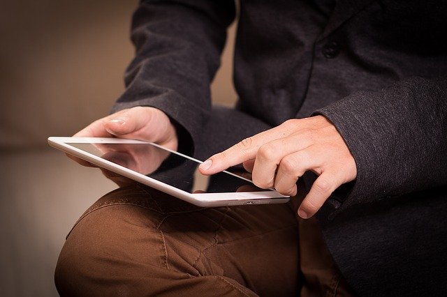 A man holding a tablet and reaching out to touch the screen