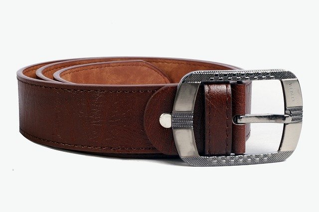 A close up of a brown leather belt, rolled up and set with the buckle facing the camera. This is to show a common object used during discipline.