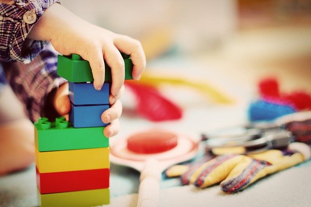 A child's hands as they play with large colorful Lego blocks