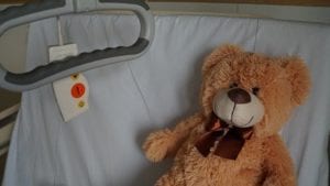 A teddy bear lying on a hospital bed