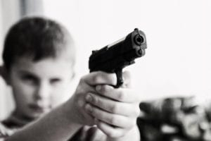 A young boy pointing a gun at the viewer
