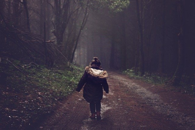 A little girl walking away into the dark woods by herself, symbolizing what a parent feels when CPS takes away their children.