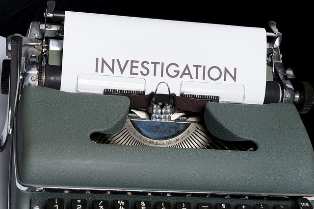 A close up of a type writer with a paper in it, saying "investigation"
