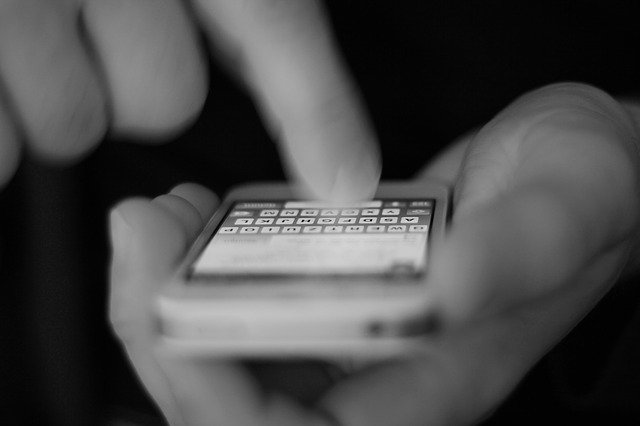 A close up of hands holding a cell phone and dialing a number, symbolizing someone making a call to authorities to report child abuse.